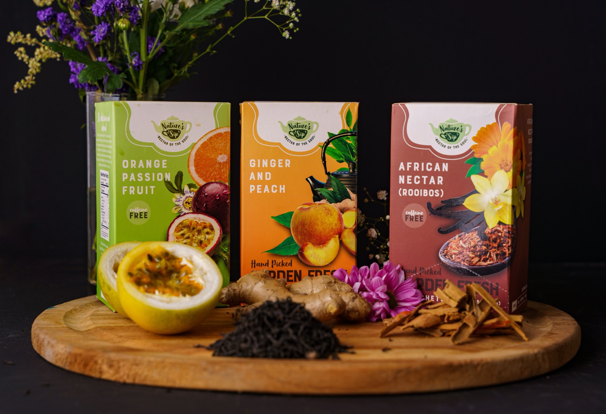 Nature's Sip Orange Passion Fruit, Ginger and Peach, and African Nectar tea boxes with fresh flowers and ginger